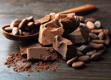 spoon with aromatic cocoa and chocolate on wooden background close up