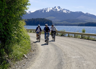 bikers biking gravel road snowcapped mountains